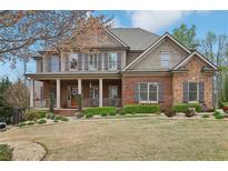 Charming two-story brick home featuring a welcoming front porch and professionally landscaped front yard at 1870 Marcia Overlook Dr, Cumming, GA 30041
