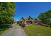 Stunning stone home with a well-manicured lawn, a long driveway, and mature trees on a sunny day at 20 Rivercreek Xing, Kingston, GA 30145