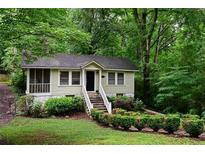 Charming home exterior featuring a screened porch, stone foundation, and lush landscaping surrounded by mature trees at 605 Harold Ne Ave, Atlanta, GA 30307