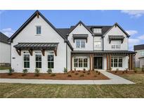 A stylish two-story home with white brick, black trim, covered entry and manicured front yard at 7785 Wild Violet Dr, Cumming, GA 30040