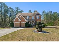 Charming brick home with a well-maintained lawn and two-car garage situated amongst lush trees at 1920 Barrington Dr, Jonesboro, GA 30236