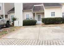 Two story townhome with two parking spaces in the driveway, and trimmed shrubs in front of the porch at 6434 Wellington Chase Ct # 6434, Lithonia, GA 30058