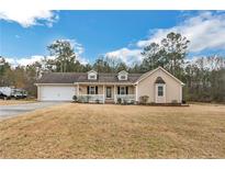 Charming single-story home with a well-manicured lawn, front porch, and attached two-car garage at 220 Timber Ln, Stockbridge, GA 30281