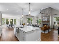 Open-concept living area boasts a stone fireplace, hardwood floors, and large windows with natural light at 3895 Overlake Dr, Cumming, GA 30041