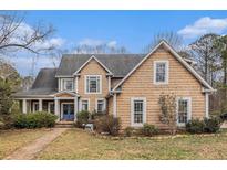 Charming two-story home with wood siding, complemented by lush landscaping and a welcoming blue front door at 905 Attaway Rd, Bowdon, GA 30108