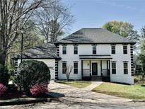 Elegant two-story home featuring a dark roof, black trim, a manicured lawn, and a welcoming front porch at 906 John Ct, Lawrenceville, GA 30046