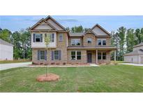 Charming two-story brick home featuring a well-manicured lawn and classic architectural details at 205 Haverling Pass, Hampton, GA 30228