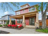 Charming two-story home with a covered porch and stone accents, complemented by red flowering shrubs at 9942 Ashton Old Rd, Douglasville, GA 30135