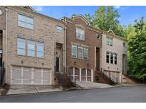 Three-story townhome with brick facade, individual garages, and landscaped entrance at 482 Pearl Cove Ct, Atlanta, GA 30350