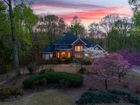 Elegant brick home with manicured landscaping and flowering trees at dusk at 4231 Carrington Ct, Douglasville, GA 30135