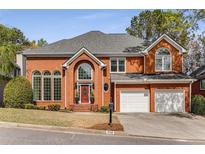 Charming brick two-story home with a well-manicured lawn, two-car garage, and elegant front entrance at 710 Glen Royal Dr, Roswell, GA 30076