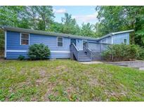 Charming single-story home featuring light blue siding, a front deck, and a well-maintained lawn with mature trees at 837 Forrest Se Cir, Atlanta, GA 30354