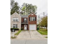 Charming two-story brick home featuring an attached garage and a beautifully manicured front yard at 1501 Eastern Sunrise Ln, Decatur, GA 30034