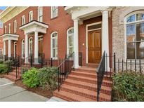 Charming red brick townhome featuring a classic facade with white pillars and a well-manicured front yard at 865 Inman Village Ne Pkwy, Atlanta, GA 30307