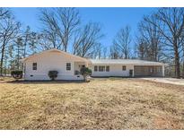 Charming single-story home with attached carport and freshly painted exterior, set on a spacious lot with mature trees at 9640 Cedar Grove Rd, Fairburn, GA 30213