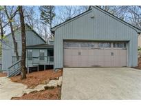 Charming home exterior featuring an attached garage and covered porch entry at 135 S Falcon Blf, Alpharetta, GA 30022