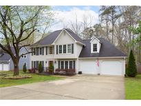 Traditional two-story home featuring a two-car garage, dark shutters, and manicured landscaping at 1315 Bustling Sw Ln, Marietta, GA 30064