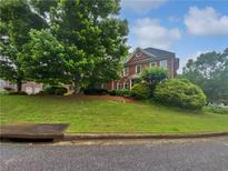 Attractive two-story brick home featuring manicured lawn, mature trees and architectural details at 2123 Tigger Ne Trce, Marietta, GA 30066