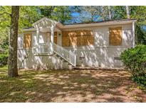Exterior front of single story home with white brick foundation, stairs and boarded up windows at 1907 Oak Valley Rd, Decatur, GA 30035