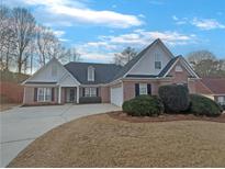Charming brick home with manicured lawn, shutters, and a long driveway leading to an attached garage at 290 Virginia Highlands, Fayetteville, GA 30215