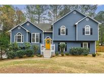 Charming two-story home featuring blue siding, a welcoming yellow front door, and well-maintained landscaping at 7660 Brentwood Ct, Cumming, GA 30040