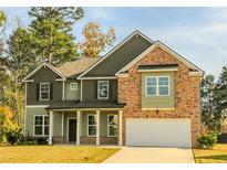 Inviting two-story home boasts a mix of brick and siding, complemented by a covered front porch and attached two-car garage at 1800 Pearson St, Loganville, GA 30052