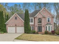 Charming two-story brick home with well-maintained landscaping and a two-car garage on a sunny day at 3887 Hickory Manor Dr, Suwanee, GA 30024
