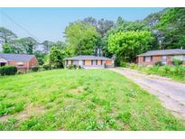 Modest single-story home with a spacious front yard and a long driveway, nestled among mature trees at 1753 Thomas Ter, Decatur, GA 30032