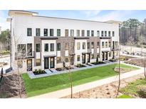 Modern townhome with manicured lawn, featuring a brick facade and contemporary black-framed windows at 7210 Summit Pl, Alpharetta, GA 30009