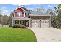 Charming two-story home featuring a manicured lawn, brick accents, and a two-car garage, all under a sunny sky at 453 Clematis Ct, Temple, GA 30179