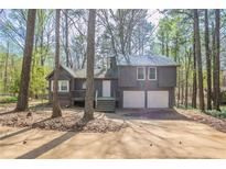 Charming home nestled among trees with a two-car garage and cozy front porch at 477 Victoria Rd, Woodstock, GA 30189