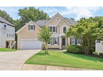 Charming two-story traditional home with tan siding, an attached garage and a well-manicured lawn at 1780 Riverglen Dr, Suwanee, GA 30024