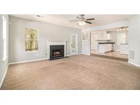 Spacious living room with fireplace, ceiling fan, and open access to kitchen area at 498 Pecan Wood Cir, Fairburn, GA 30213