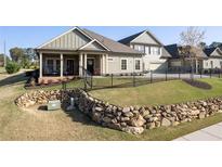 Charming single-Gathering home featuring manicured lawn, black fence, and covered front porch with black railings at 57 Cedarcrest Village Ln, Acworth, GA 30101