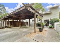 Attached carport featuring a wooden pergola cover and walkway to the cozy townhome's front door at 2060 Clairmeade Ne Way, Atlanta, GA 30329