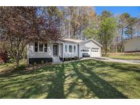 Charming single-story home featuring an attached two-car garage, a well-manicured lawn, and mature trees at 90 Chimney Rise Ct, Stockbridge, GA 30281