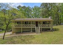 Charming single-story home featuring a covered front porch, green lawn, and mature trees at 10 Powder Dr, Dallas, GA 30157