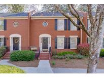 Beautiful brick townhome with black shutters, manicured landscaping, and inviting entrance at 102 Defoors Mill Dr, Atlanta, GA 30318