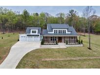 Stunning aerial view of a home with a large driveway and an attached three-car garage surrounded by lush greenery at 3078 Turning Creek Trl, Dacula, GA 30019