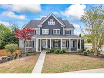 Charming two-story home boasts a covered porch, stone accents, and manicured landscaping at 2031 Democracy Dr, Buford, GA 30519