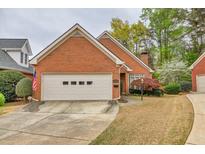 Charming brick home features a two-car garage, manicured lawn and mature trees at 2330 Burlington Ln, Snellville, GA 30078