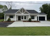 Charming one-story home with a black roof, white siding and a large driveway at 4824 Highway 20 Se, Conyers, GA 30013