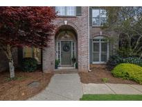 Charming brick home entrance featuring an arched doorway and a well-maintained landscaped yard at 5450 Piney Grove Dr, Cumming, GA 30040