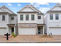 Charming two-story home with brick driveway, stone accents, white siding, and a two-car garage at 756 Stickley Oak Way, Woodstock, GA 30189