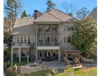 Elegant stone home featuring multiple balconies and a stone patio with outdoor seating and a fire pit at 6316 Woodlake Dr, Buford, GA 30518