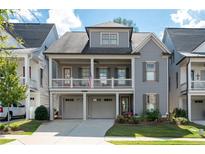Charming two-story home featuring a welcoming front porch, attached garage and manicured lawn at 319 Riverton Way, Woodstock, GA 30188