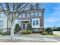 Brick townhome featuring manicured landscaping, a covered entrance, and symmetrical shrubbery at 4323 Tacoma Trce, Suwanee, GA 30024