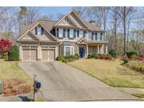 Traditional two-story home with a two-car garage, manicured lawn, and mature trees providing shade at 5808 Deer Crossing Dr, Sugar Hill, GA 30518