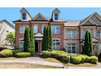Charming brick townhome featuring dormer windows and manicured landscaping, creating a welcoming curb appeal at 7620 Stoneridge Dr, Atlanta, GA 30328