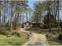 Charming home nestled in wooded area featuring a long driveway and mature trees at 302 Chattahoochee Way, Woodstock, GA 30188